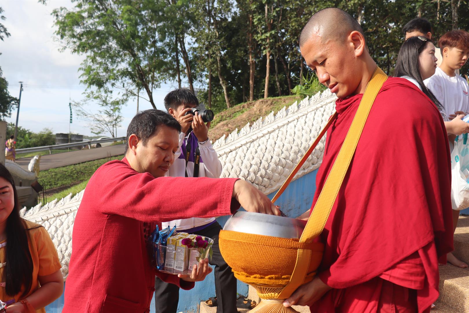 Community members offering rice and dried food at the Annual Tak Bat Devo Ceremony 2025