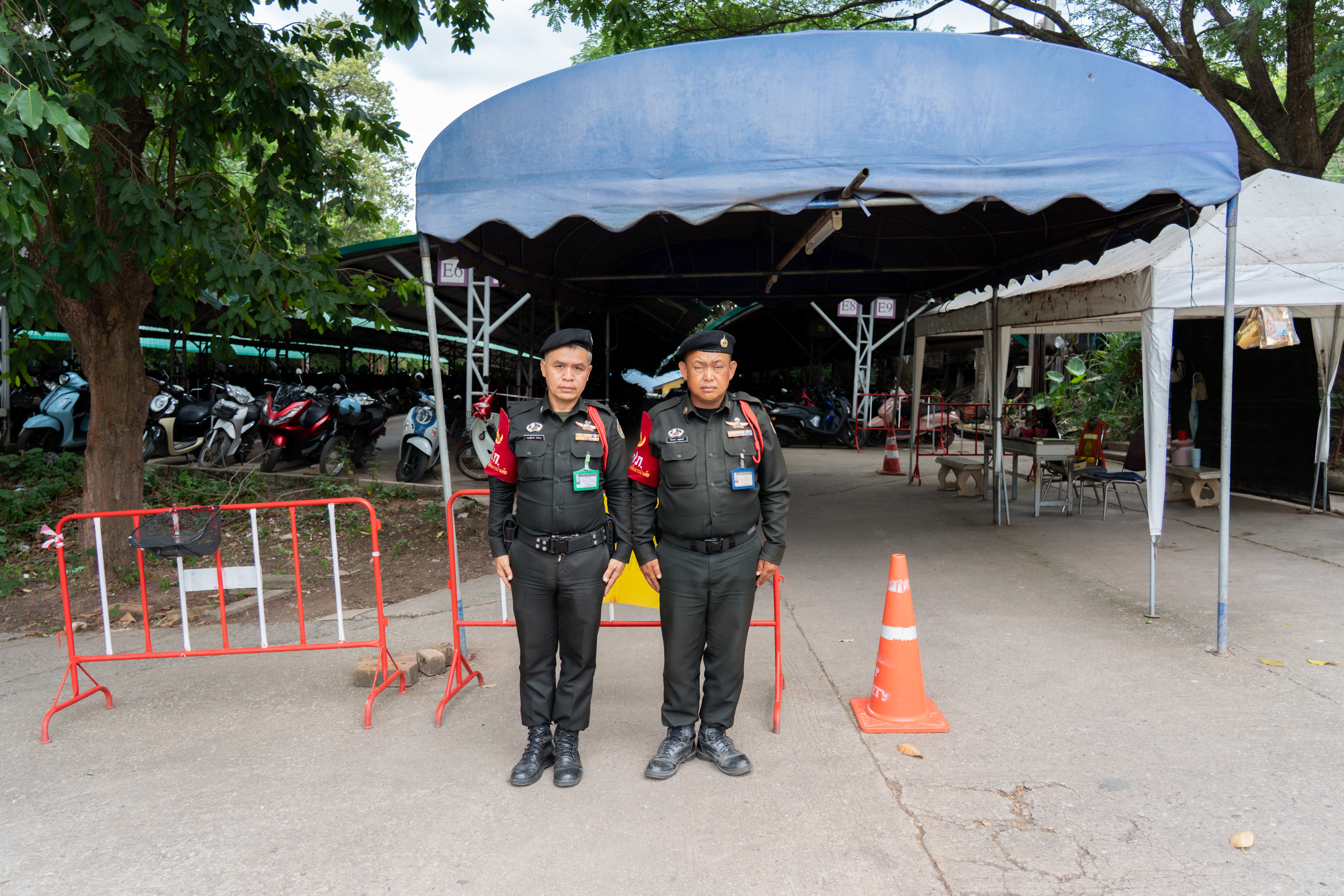 Security officer inspecting vehicles at parking entrance, University of Phayao