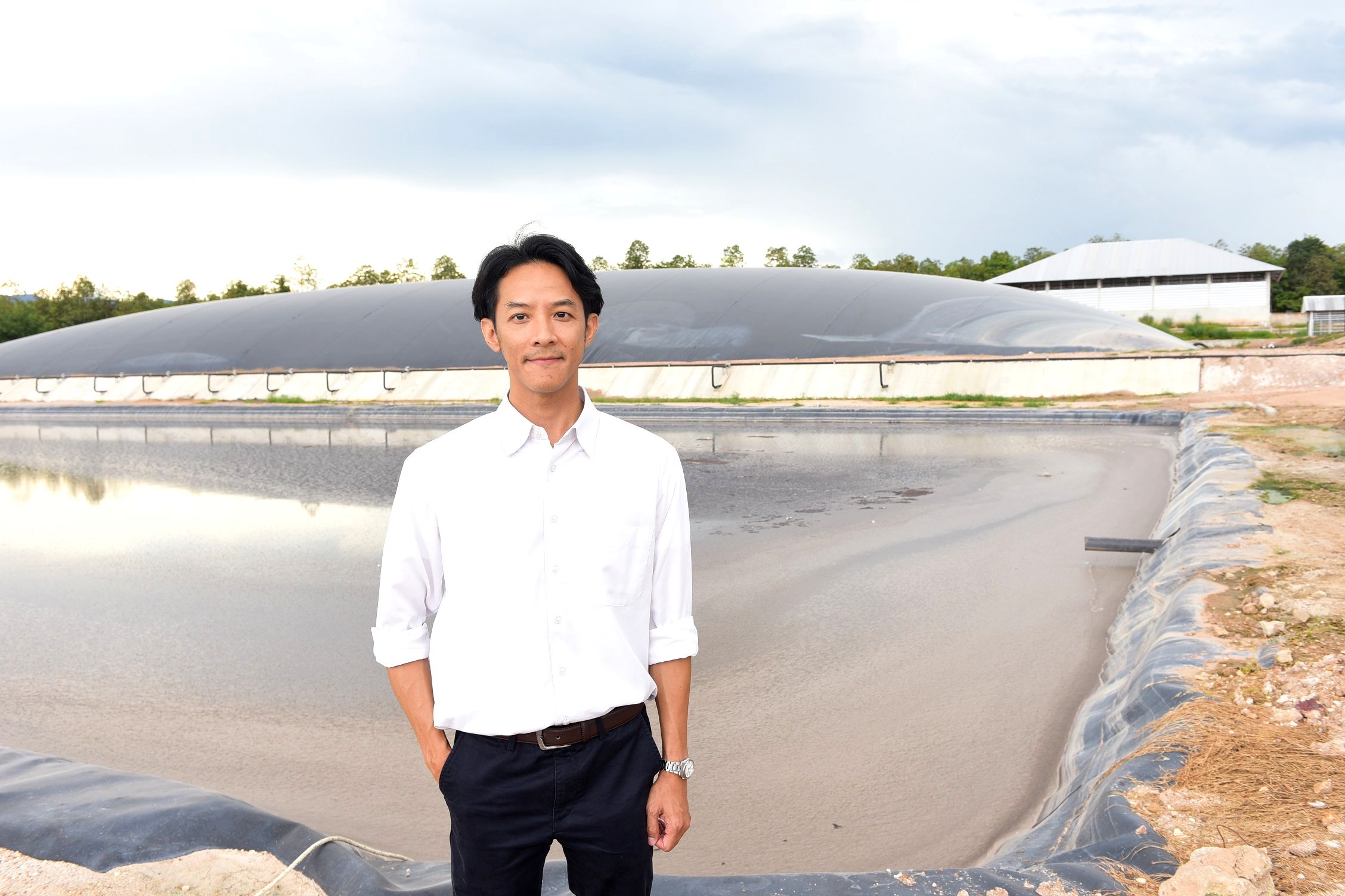 Graduate with green job standing in front of aquaculture ponds